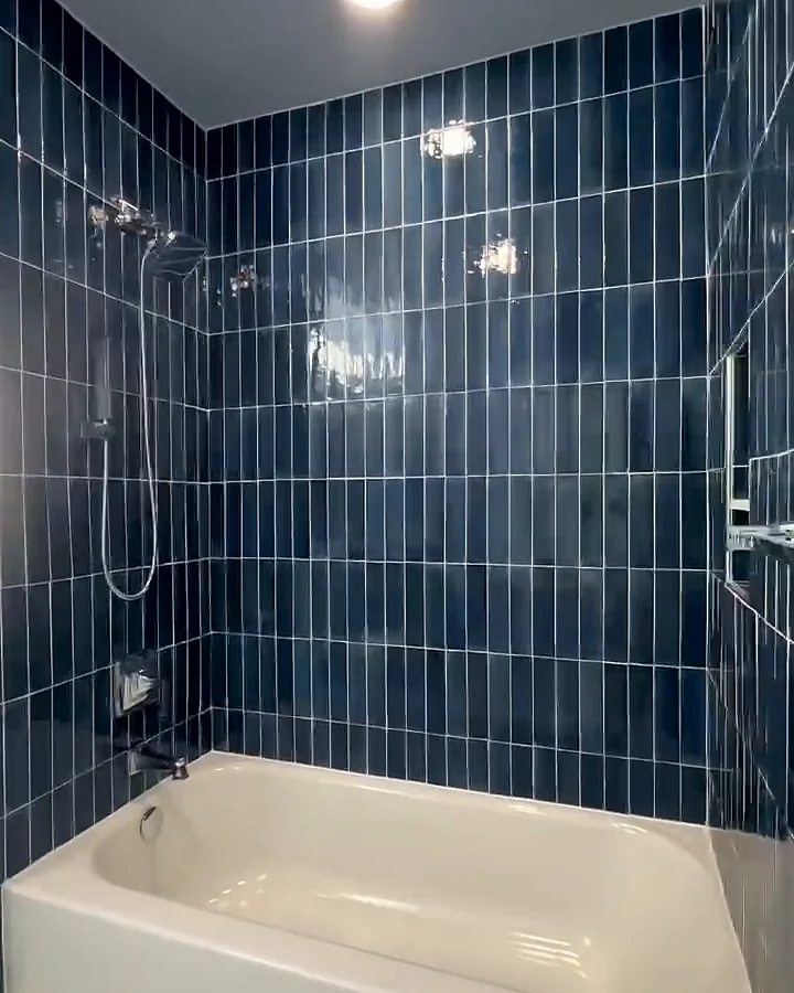 Remodeled bathroom with navy vertical subway tile, tub and shower, and recessed niche