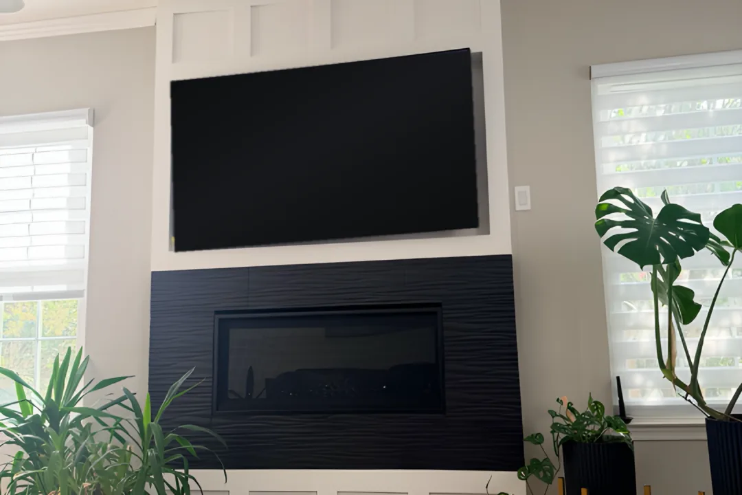 Finished media wall with white board-and-batten paneling and a black textured fireplace surround
