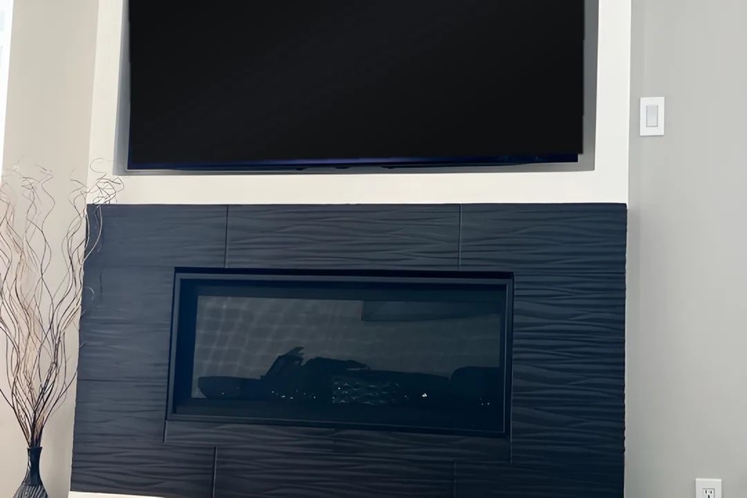 Close-up of the black textured fireplace surround and paneled media wall